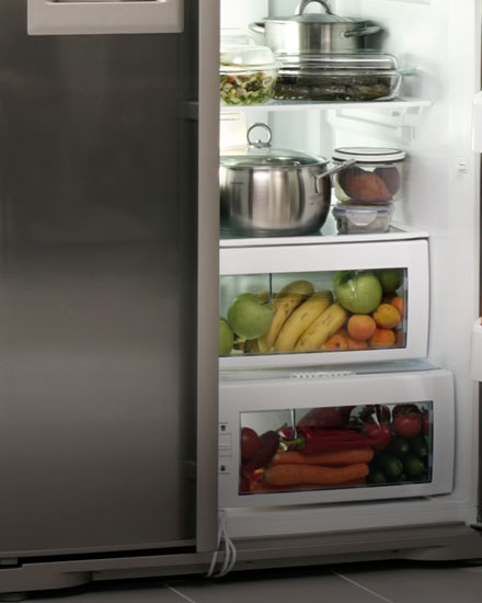 An open refrigerator door is fully stocked with fruits and vegetables. 