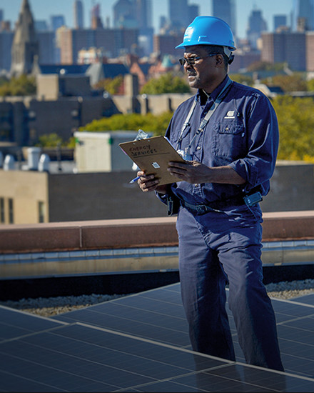 A Con Edison employee standing amid a rooftop solar installation.