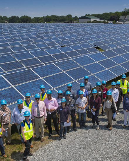 A team of Con Edison employees standing near a large solar panel installation