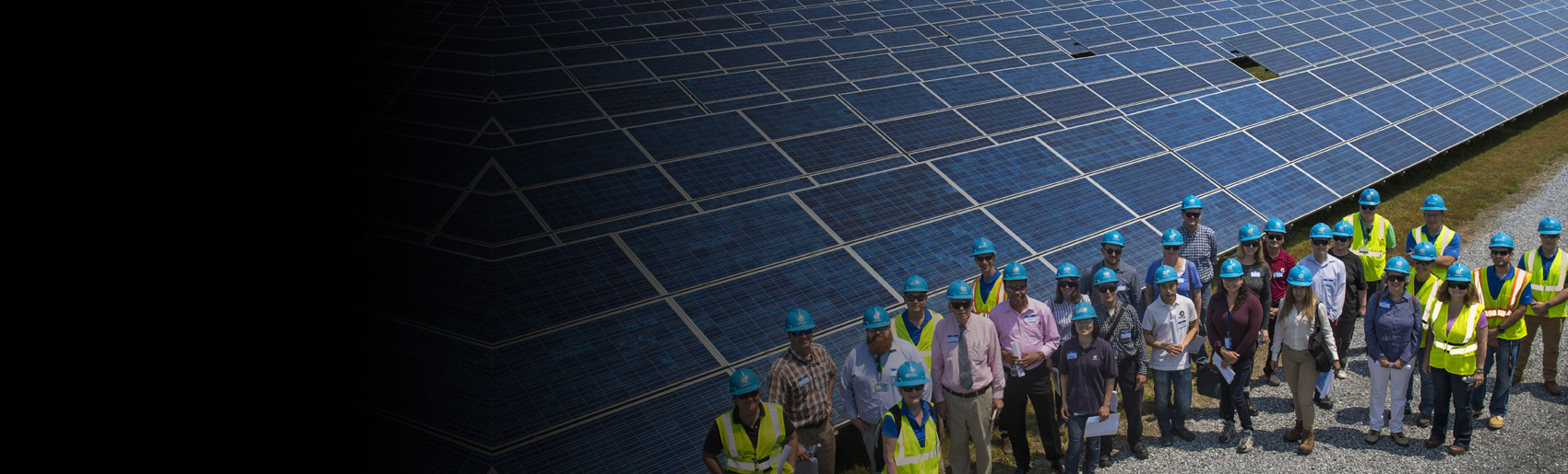 Un equipo de empleados de Con Edison de pie cerca de una gran instalación de paneles solares
