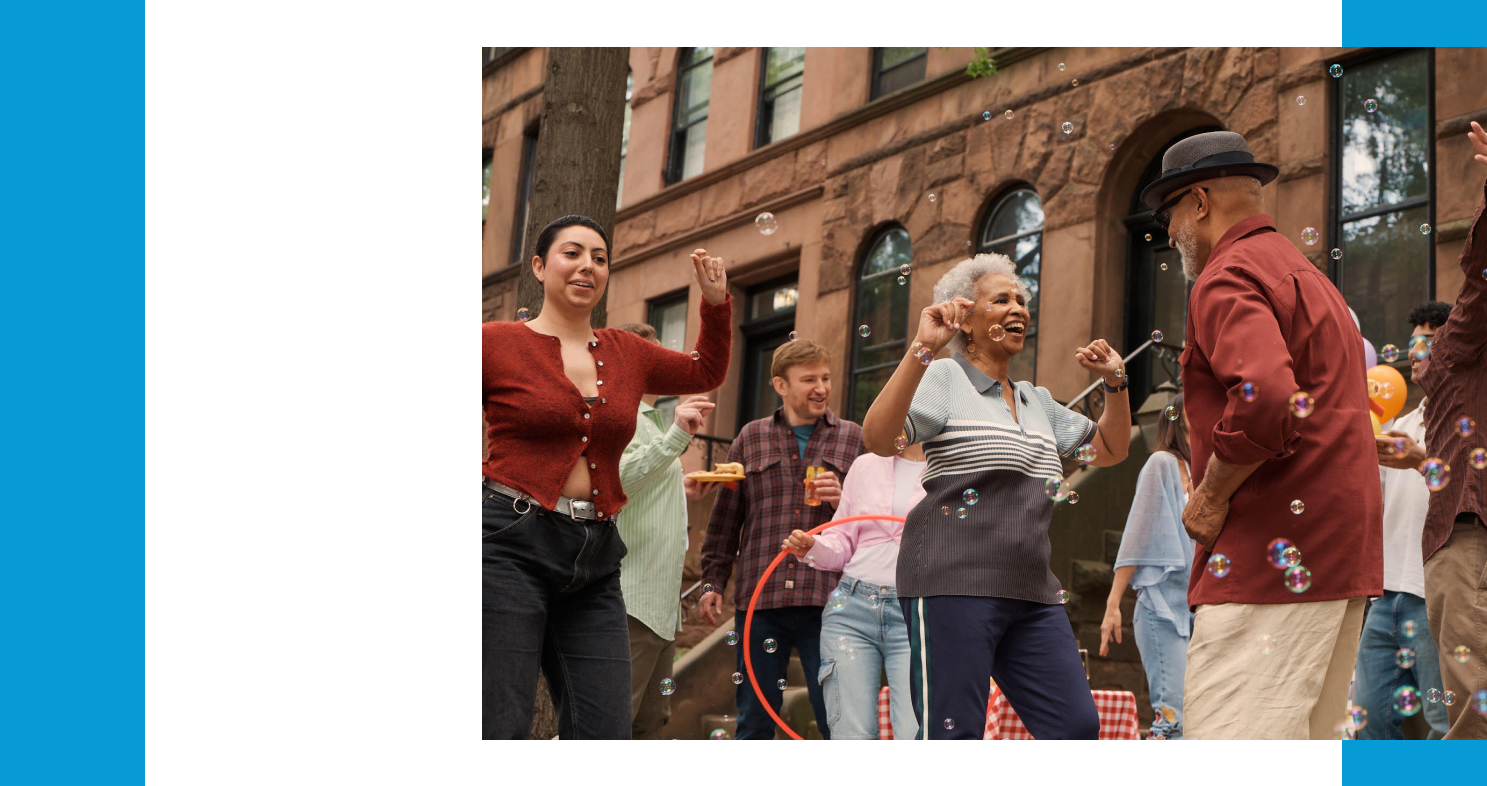 A group of people dancing outside a brownstone building. Bubble are in the air around them.