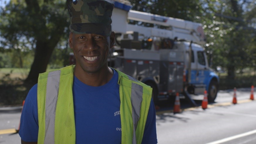 A utility worker poses in a military hat.