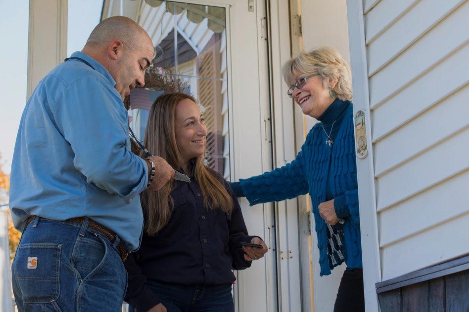 Two outreach members speak to a woman at her front door.