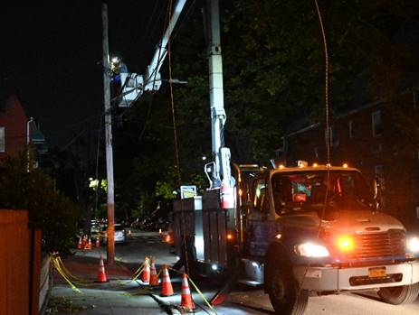 A worker in an overhead bucket truck making repairs during the night.
