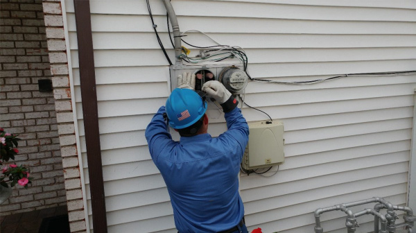 A worker installing a smart meter on an exterior wall.