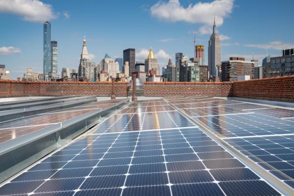 Solar panels on a rooftop with the New York City skyline in the background.