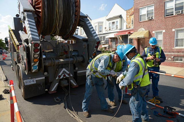 Con Edison crews install electrical wire upgrades on a residential street.