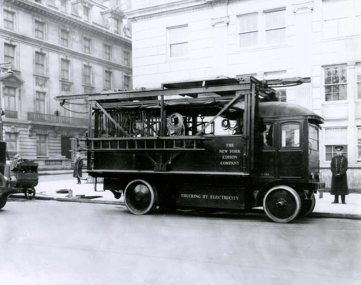 A black and white photo of a historic Con Edison truck parked on the streets of New York City.