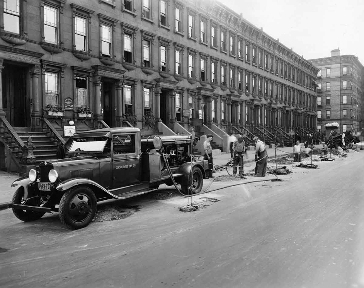 Black and white photo of Con Edison workers unloading equipment onto a city street.