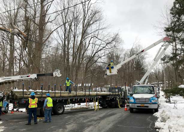 Con Edison work trucks on a snow-covered street repairing damage after the Riley-Quinn storm events. 
