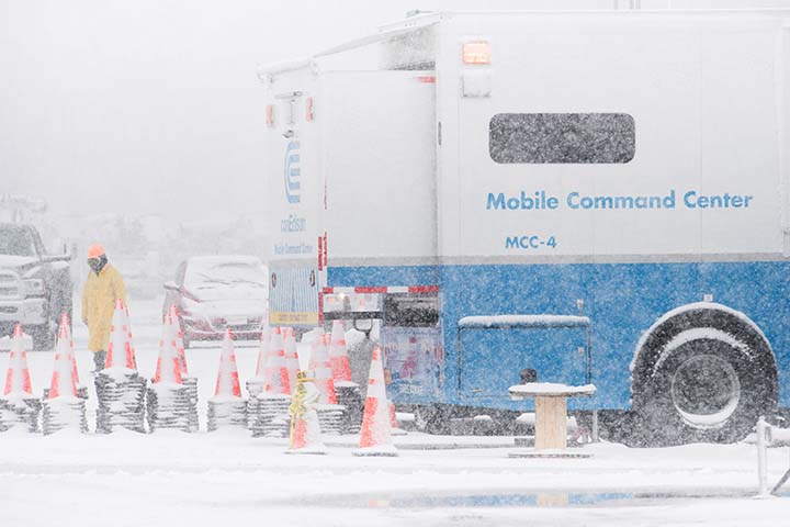 A utility truck and worker in a snowstorm.