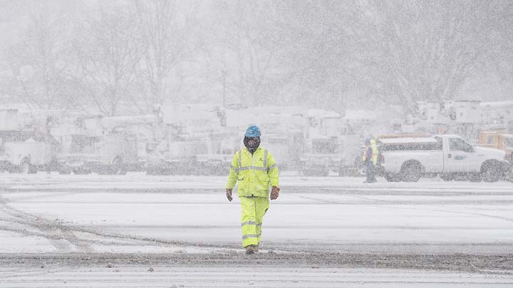 A Con Edison worker is walking through a snow covered recovery staging area.