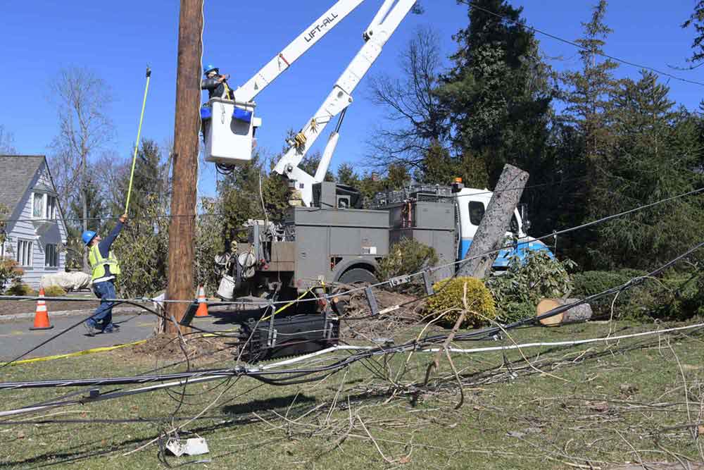 A worker in a bucket truck is repairing damage to overhead poles after the Riley-Quinn storm events. 