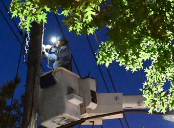 A worker in a bucket truck repairs overhead wires.