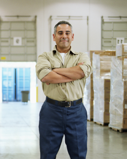 A man standing in a warehouse with his arms crossed.