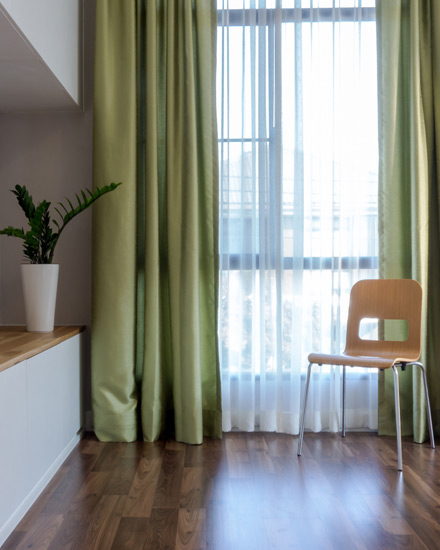 Sunny windows framed with green drapes.