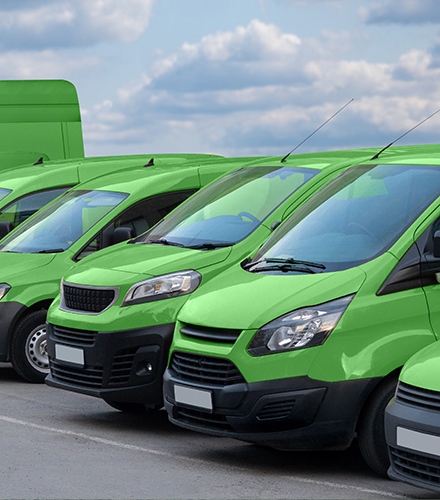 A fleet of green electric vans parked in a lot.