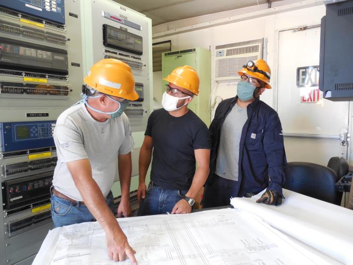 Workers looking at a diagram while wearing masks.