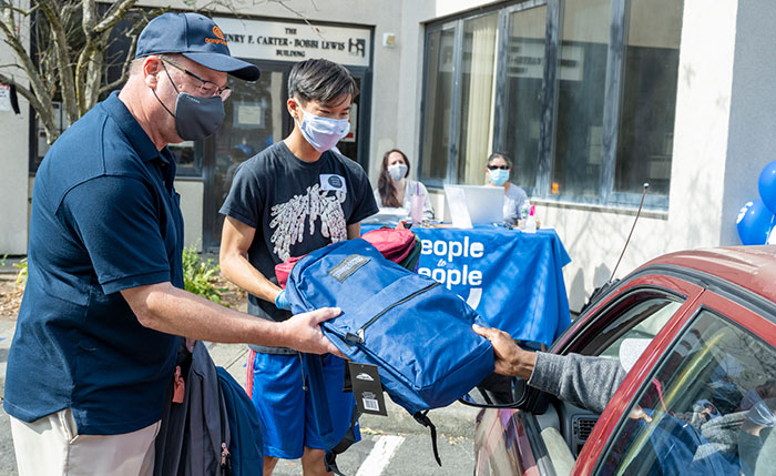 Neil Winter, the president of the People to People Board of Directors, left, delivers backpacks to one family with the assistance of volunteer Nick Ng, right, from New City.