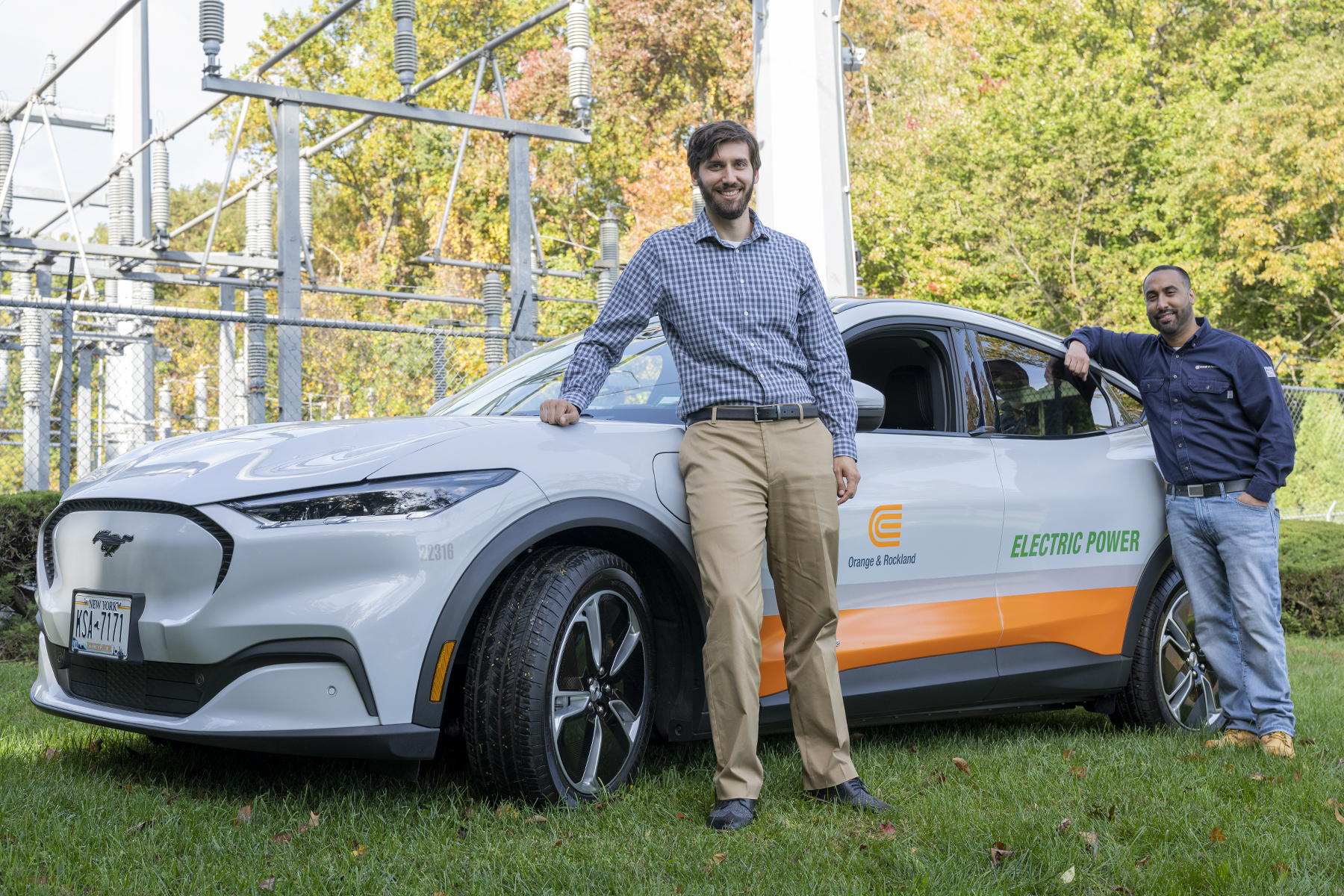 Two O&R employees standing in front of electric vehicle Mustang Mach-E