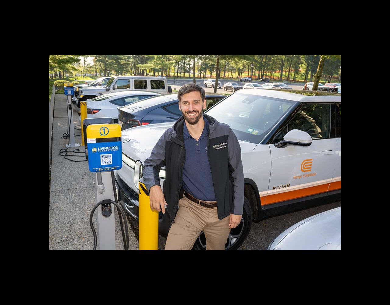 An Orange & Rockland employee stands next to an electric vehicle charging station.
