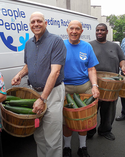 People in front of van holding vegetables to donate