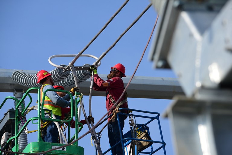 Workers connecting cables to a utility pole.